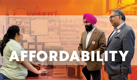 Naheed Nenshi and Gurtej Singh Brar talking with a grocery store cashier.